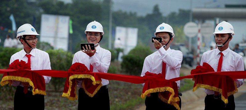 Những cán bộ ngành Giao thông tranh thủ  chụp ảnh selfie bằng điện thoại thông minh trong khi đang nâng dải băng đỏ chờ cắt băng khánh thành cao tốc Nội Bài - Lào Cai vào tháng 9/2014.